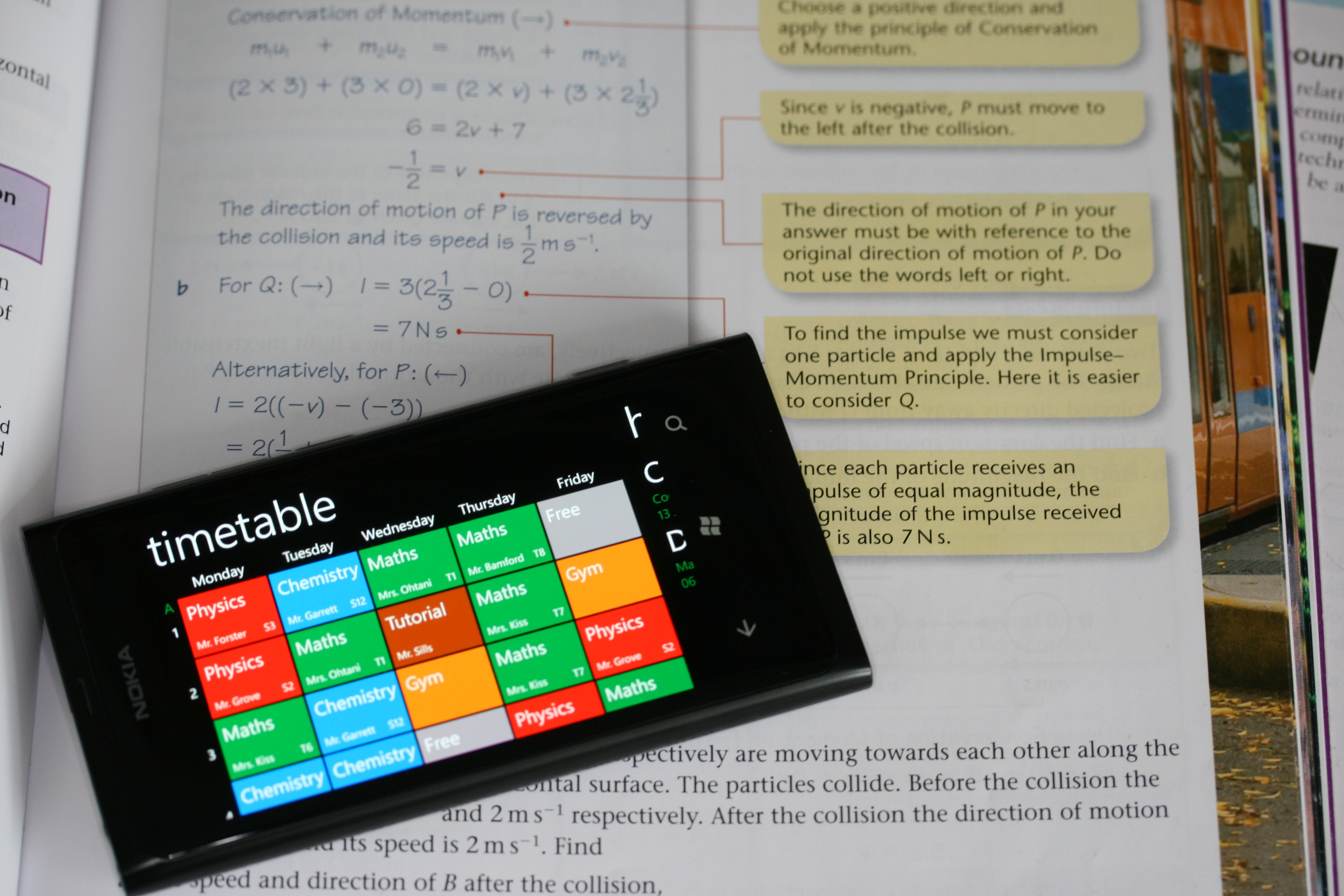 A weekly timetable on a phone lying across an open textbook.